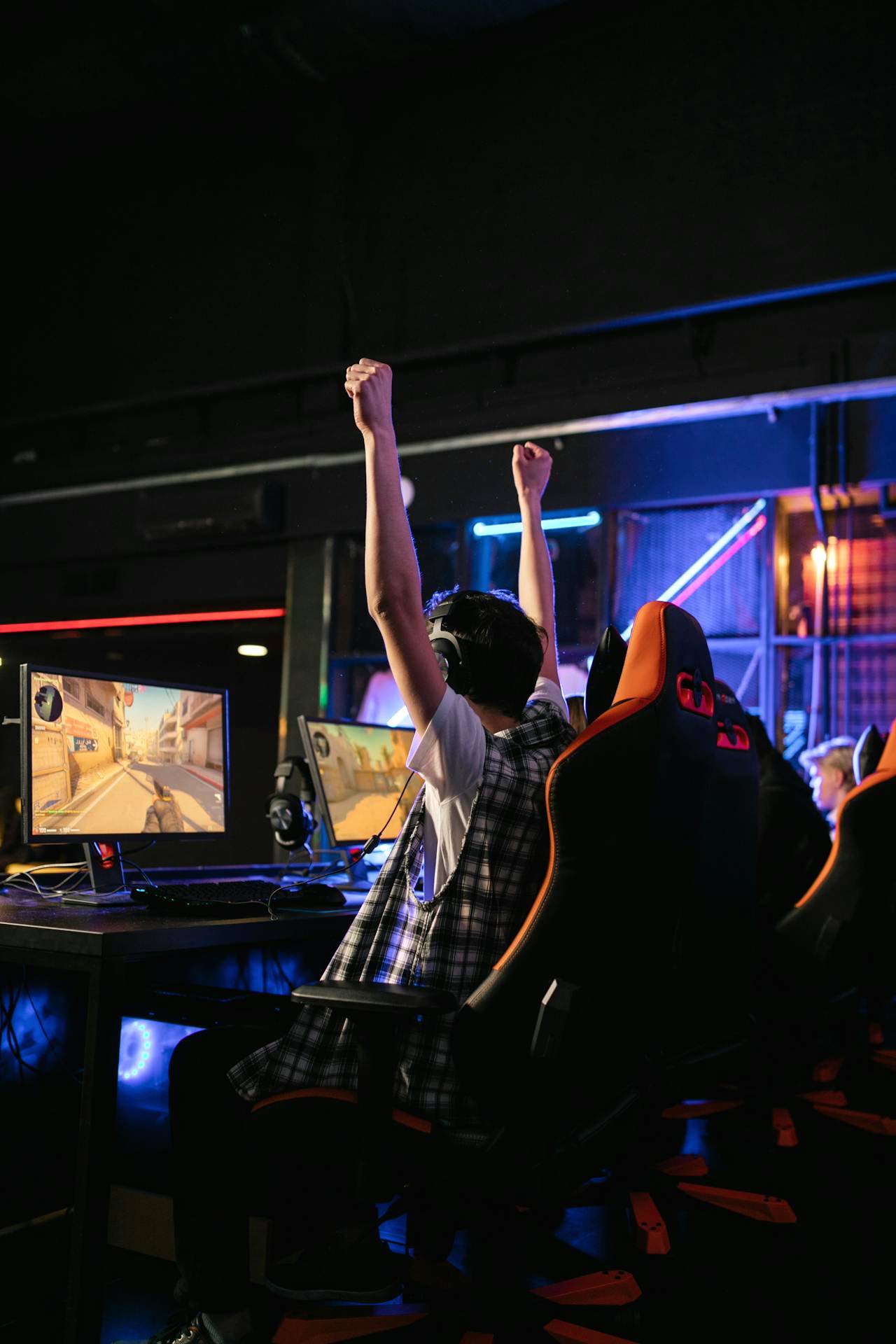Gamer celebrating a victory at a computer gaming station with a custom-built gaming computer.